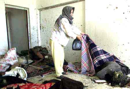 Palestinian woman looks at dead bodies 